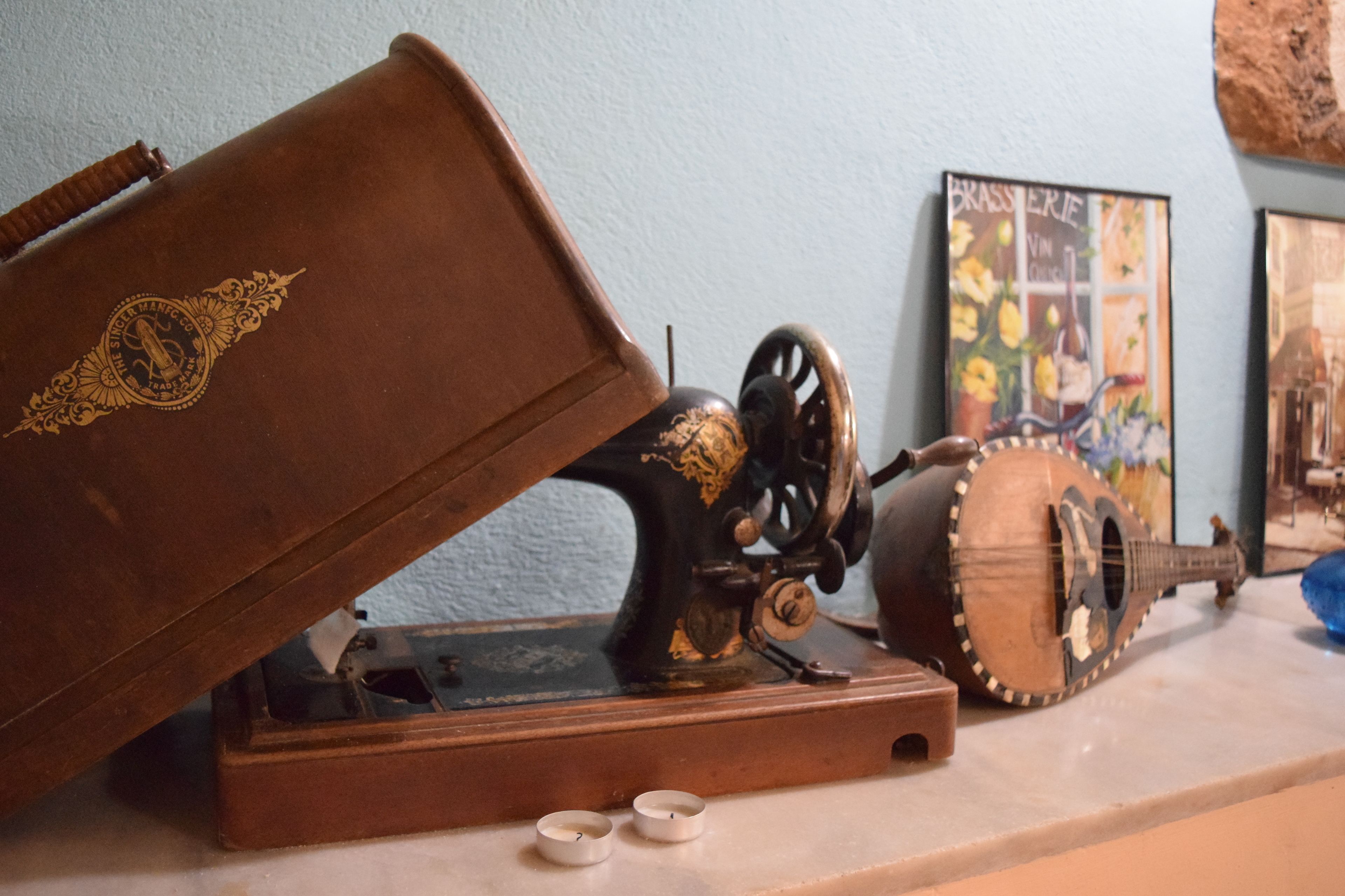 Una máquina de coser, una guitarra y un cuadro en un marco sobre una mesa.