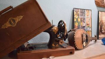 Una máquina de coser, una guitarra y un cuadro en un marco sobre una mesa.