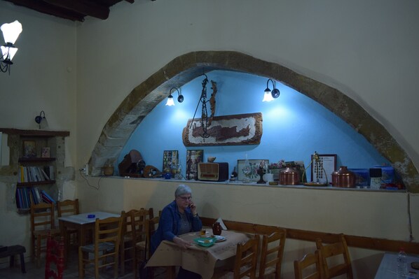 Un comedor rústico con un arco de piedra, sillas de madera y una mesa con mantel.