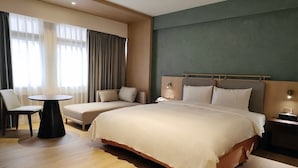 Una camera d'albergo con un letto grande, un letto più piccolo, un tavolino rotondo e una sedia.