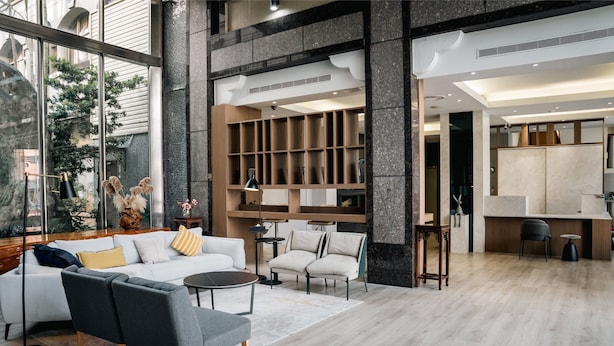Un interno moderno con zona living caratterizzata da un divano, poltrone e tavolino. È presente un angolo cottura con mobili e un tavolo da pranzo.