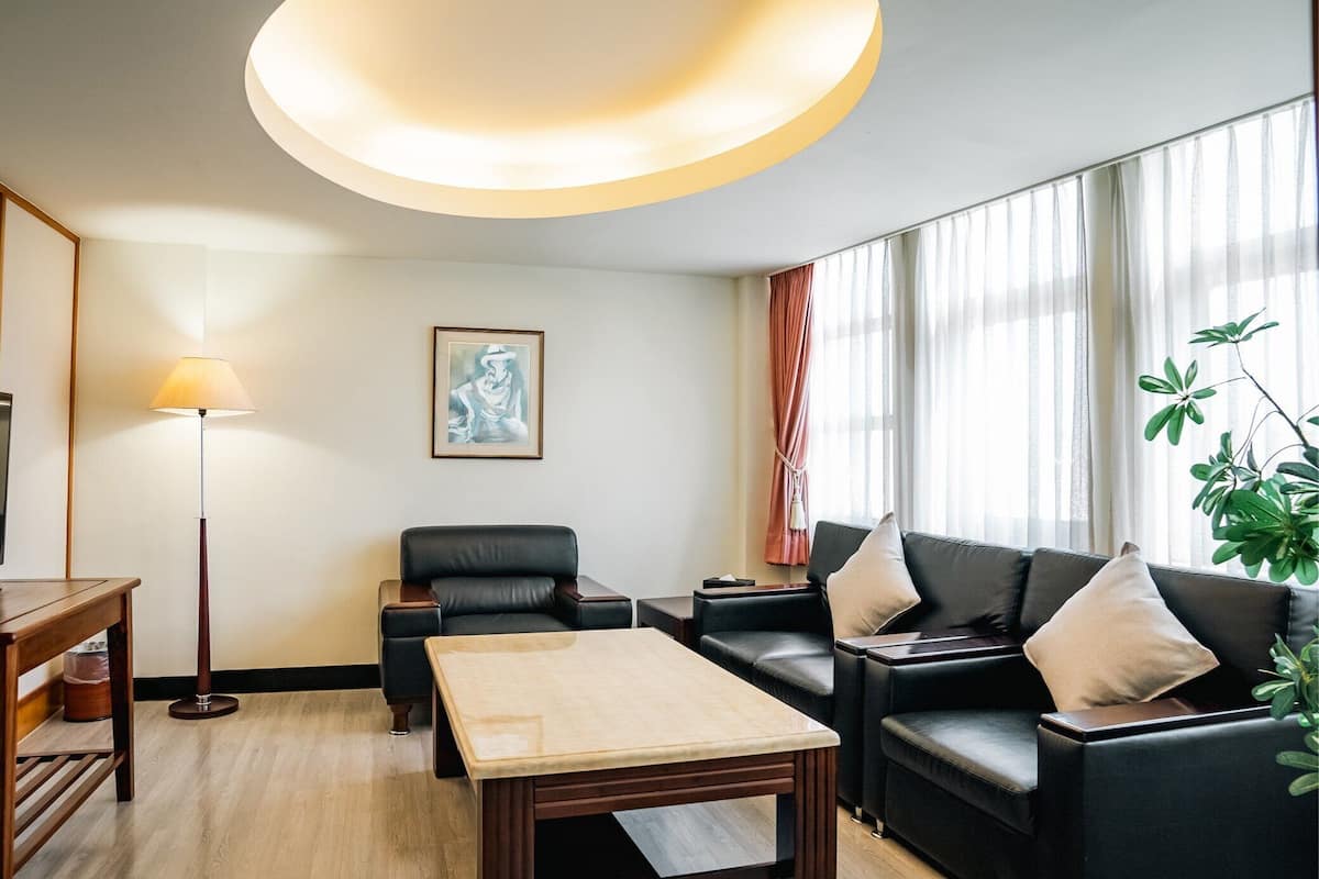Uma sala de estar moderna com sofá, mesa de centro, abajur e um quadro na parede.