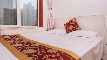 A hotel room with a bed, a window, and a view of tall buildings.