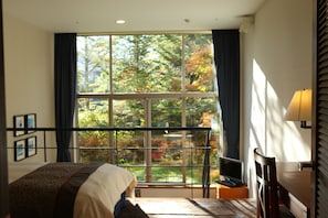 A bedroom with a large window, a bed, a desk, and a chair. - Hotel Harvest Kyukaruizawa (Karuizawa)