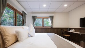 A hotel room with a large bed, a desk, a chair, a TV, and a window with curtains. - Guanwu Villa (Taian)