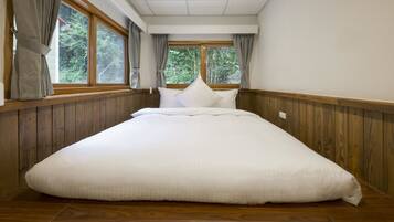 Una cama grande en una habitación con paneles de madera y vistas a zonas verdes a través de las ventanas.