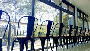 A row of black chairs with wooden tops, arranged in a classroom or meeting room with large windows and a tiled floor. - Guanwu Villa (Taian)