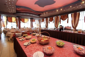 A buffet setup in a dining area with tables, chairs, and various food items.
