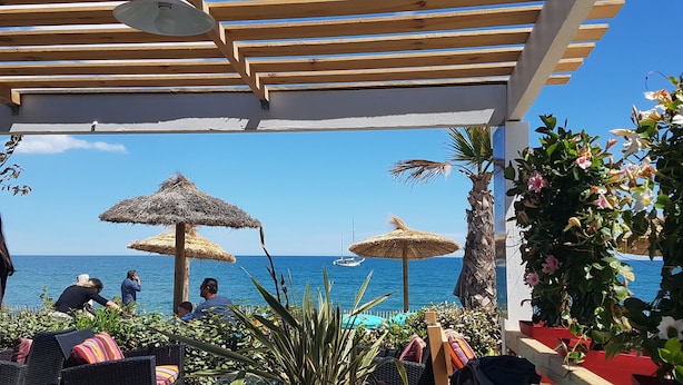 A covered outdoor seating area with thatched umbrellas, a pool, and a view of the sea. - La Vieille Demeure (Torreilles)