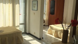 A hotel room with a bed, a small table, a vase with flowers, and a door leading to another room. - Tango (Golden Sands)