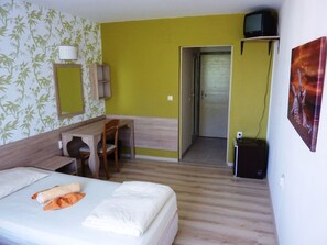 A hotel room with a bed, a desk, a chair, a TV, and a door leading to a bathroom. - Hotel Zarya- All Inclusive Light (Golden Sands)