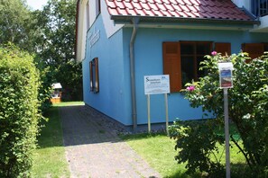 A building with a blue exterior, a red-tiled roof, and a sign indicating it is a Strandhaus named Jonathan. - Beach house Jonathan 4 OG (Wustrow)