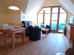 A dining area with a wooden table, chairs, and a large window with a view of the outdoors. - Beach house Jonathan 4 OG (Wustrow)