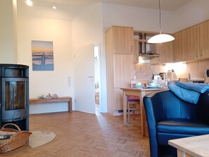 A modern kitchen with wooden cabinets, a dining table, and a blue sofa. - Beach house Jonathan 4 OG (Wustrow)