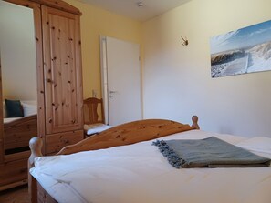 A bedroom with a wooden bed, a wardrobe, a door, and a painting on the wall.