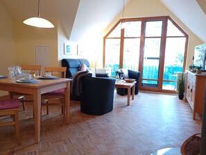 A dining area with a wooden table, chairs, and a large window with a view of the outdoors.