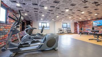 A gym with brick walls, a ceiling covered in newspaper clippings, and various exercise equipment.