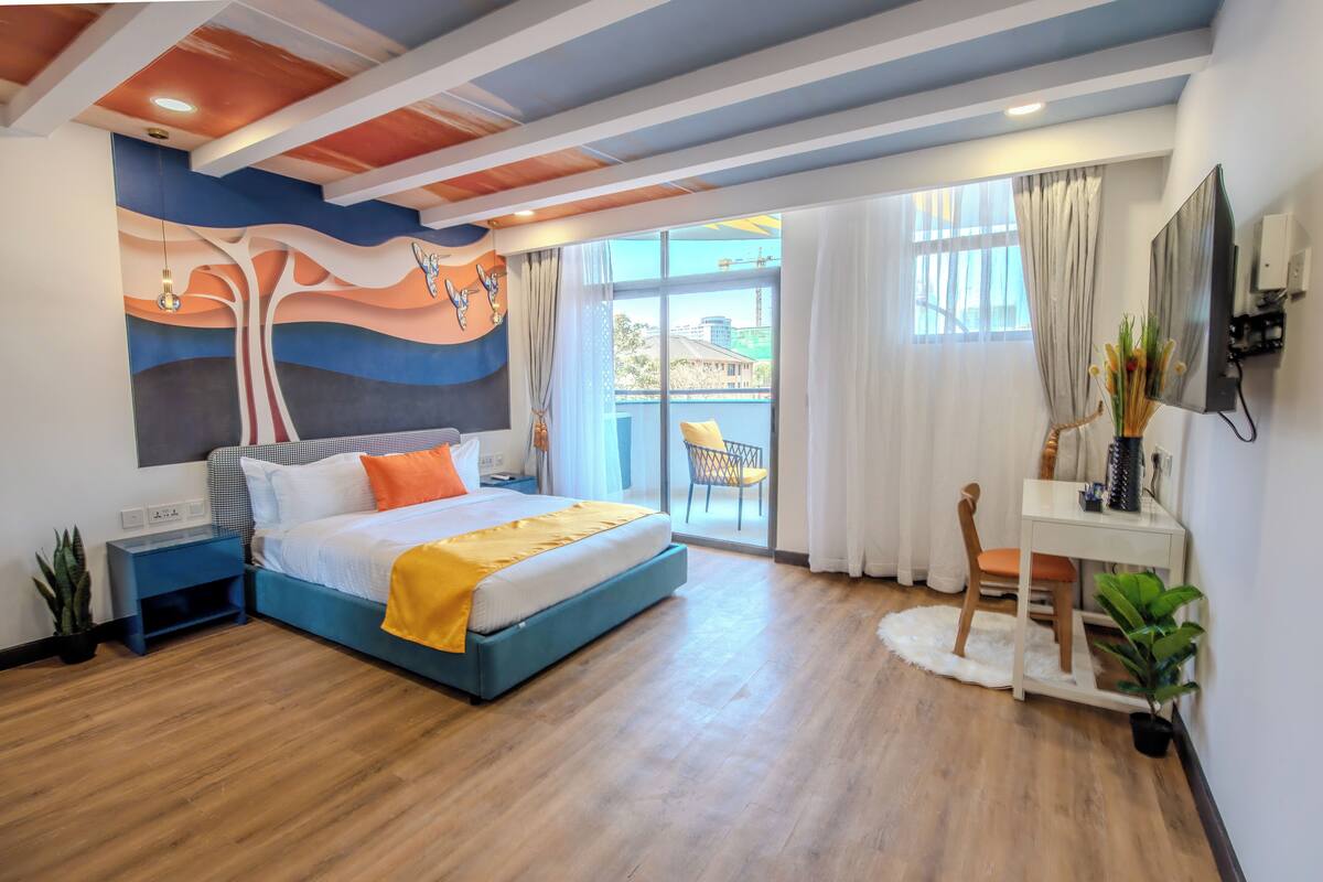 A modern bedroom with a bed, bedside table, and a desk with a chair.