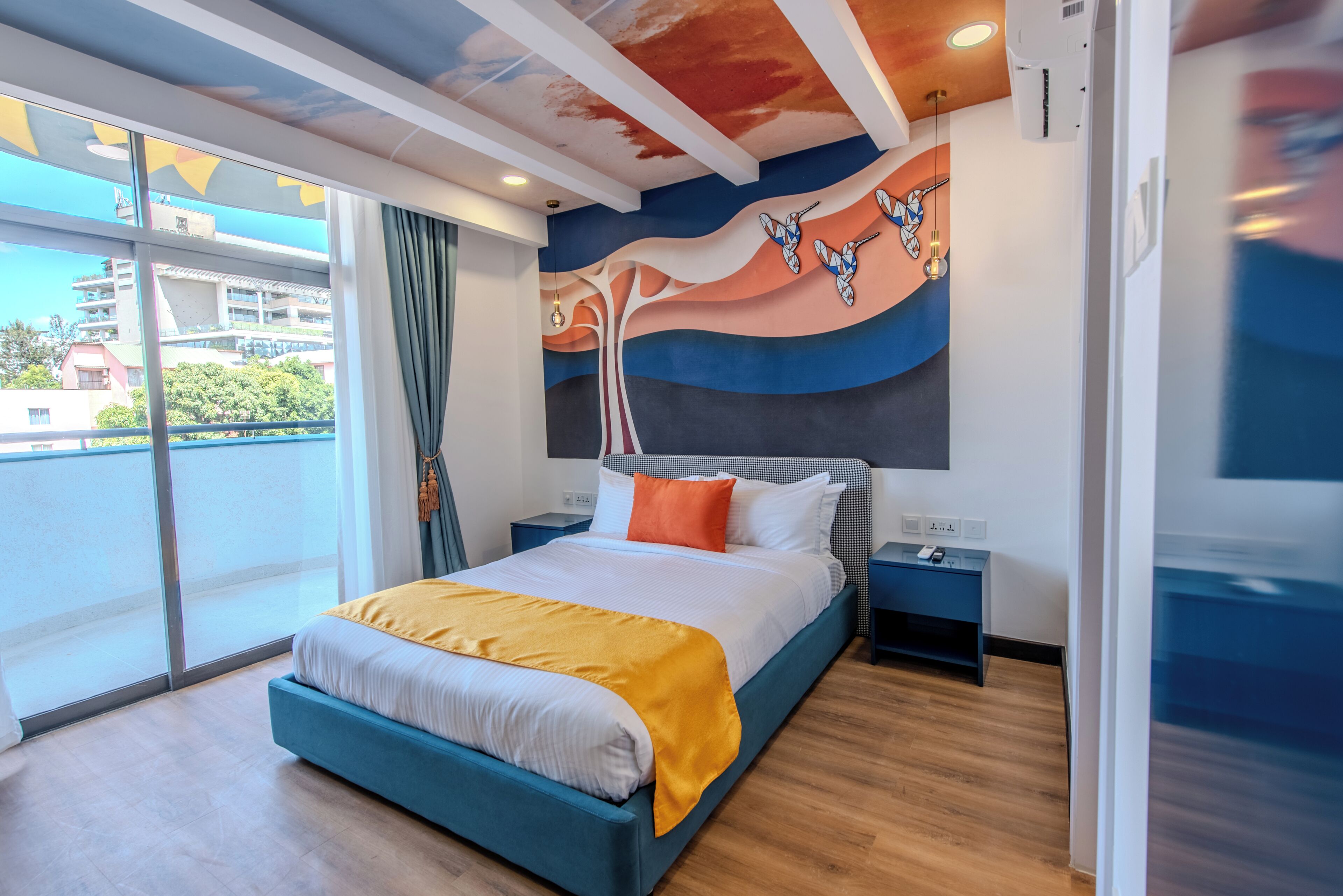 Une chambre d’hôtel moderne dotée d’un grand lit, offrant une vue sur la ville et présentant un design de plafond original.