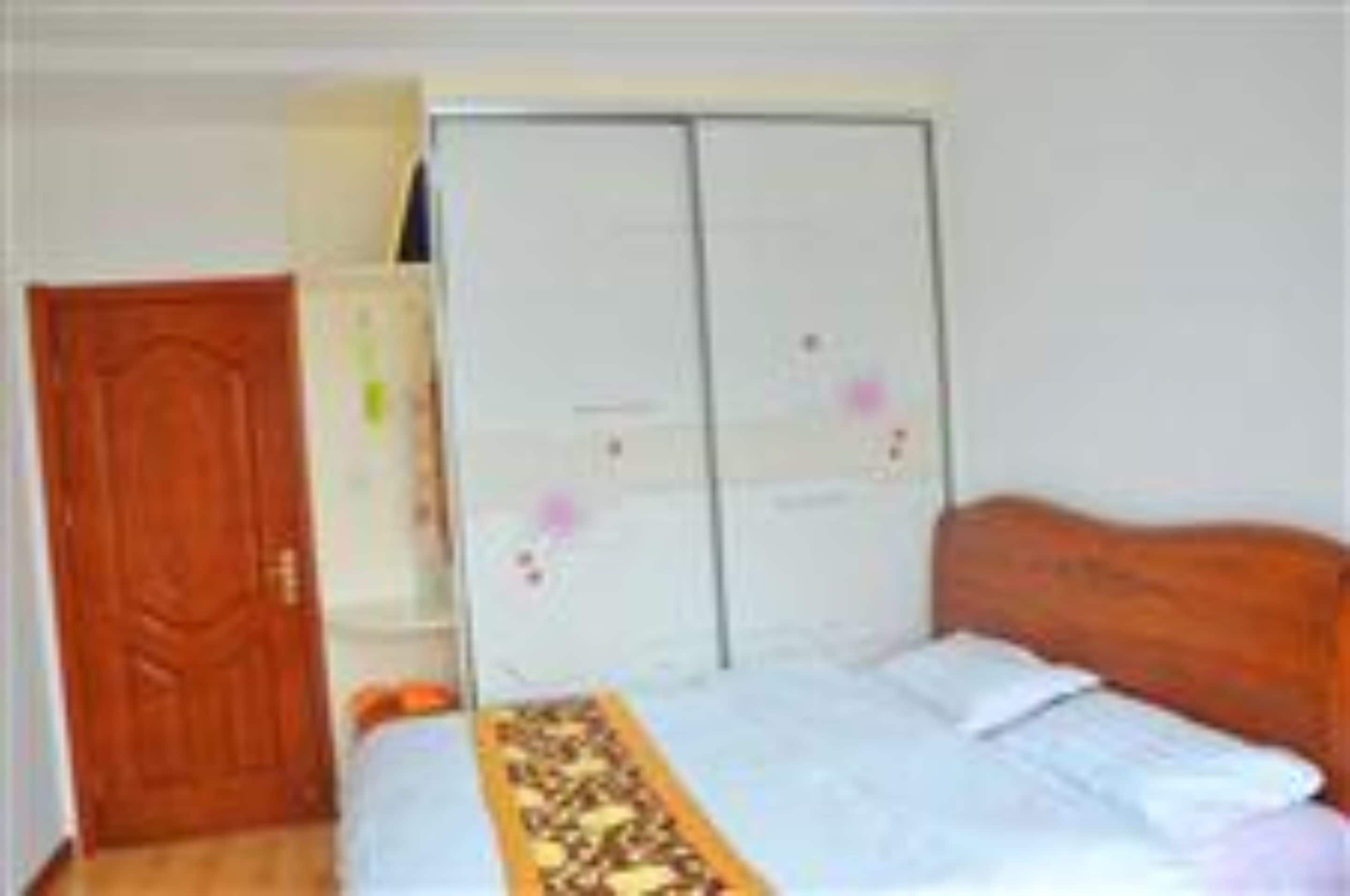 A bedroom with a bed, a wardrobe, and a door.