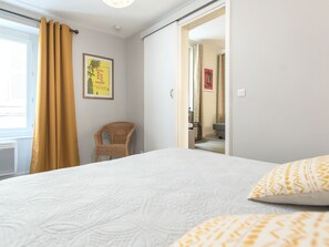 A bedroom with a bed, a chair, and a door leading to a bathroom. - Charming in the heart of Avignon (Avignon)