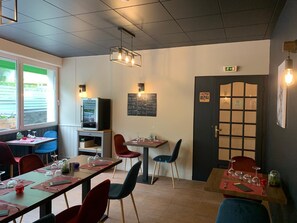 A restaurant interior with tables, chairs, and a menu board. - Hôtel Le Regis (Mont-Dore)