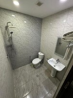 Een badkamer met douche, toilet en wastafel.