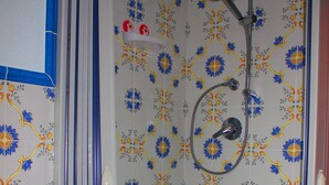 A bathroom with a shower, a sink, and patterned tiles. - Casale Racalmare (Grotte)