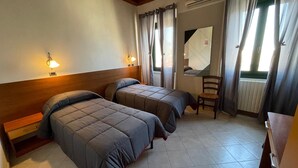 Een kamer met twee bedden, een stoel, een spiegel en een radiator.