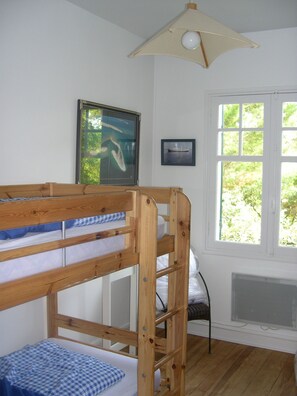 A bunk bed room with a window, a framed picture, and a ceiling light fixture.