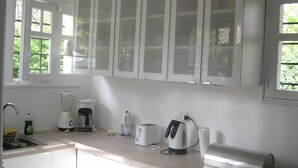 Una cocina con armarios blancos, cafetera, tostadora y licuadora sobre la encimera.