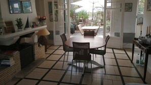 Comedor con una mesa redonda y sillas, una araña y vista al patio exterior.