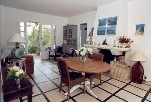 A dining area with a round wooden table and chairs, a cabinet, and a fireplace with a vase of flowers.