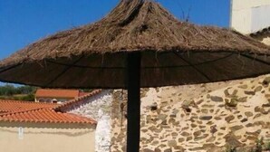 Una estructura con techo de paja y una piscina al fondo.