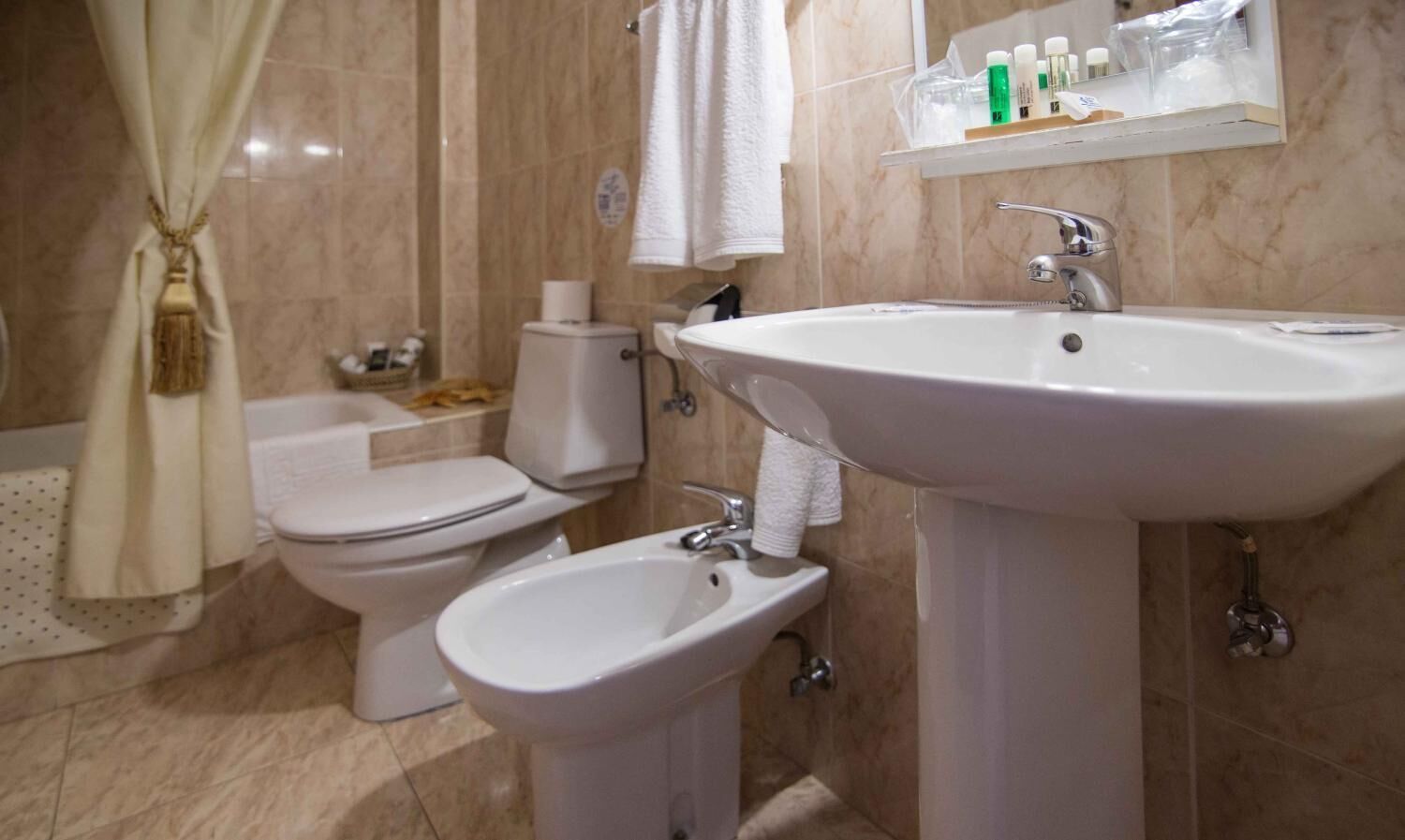 Une salle de bain équipée de toilettes, d’un bidet et d’un lavabo.