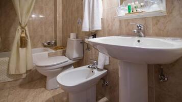 Une salle de bain équipée de toilettes, d’un bidet et d’un lavabo.