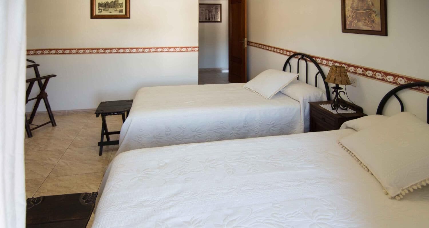 Ein Hotelzimmer mit zwei Betten, einem kleinen Tisch, einem Stuhl und einer Lampe.