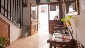 Vestíbulo de hotel con una escalera, un mostrador de recepción y un cartel que indica la salida.