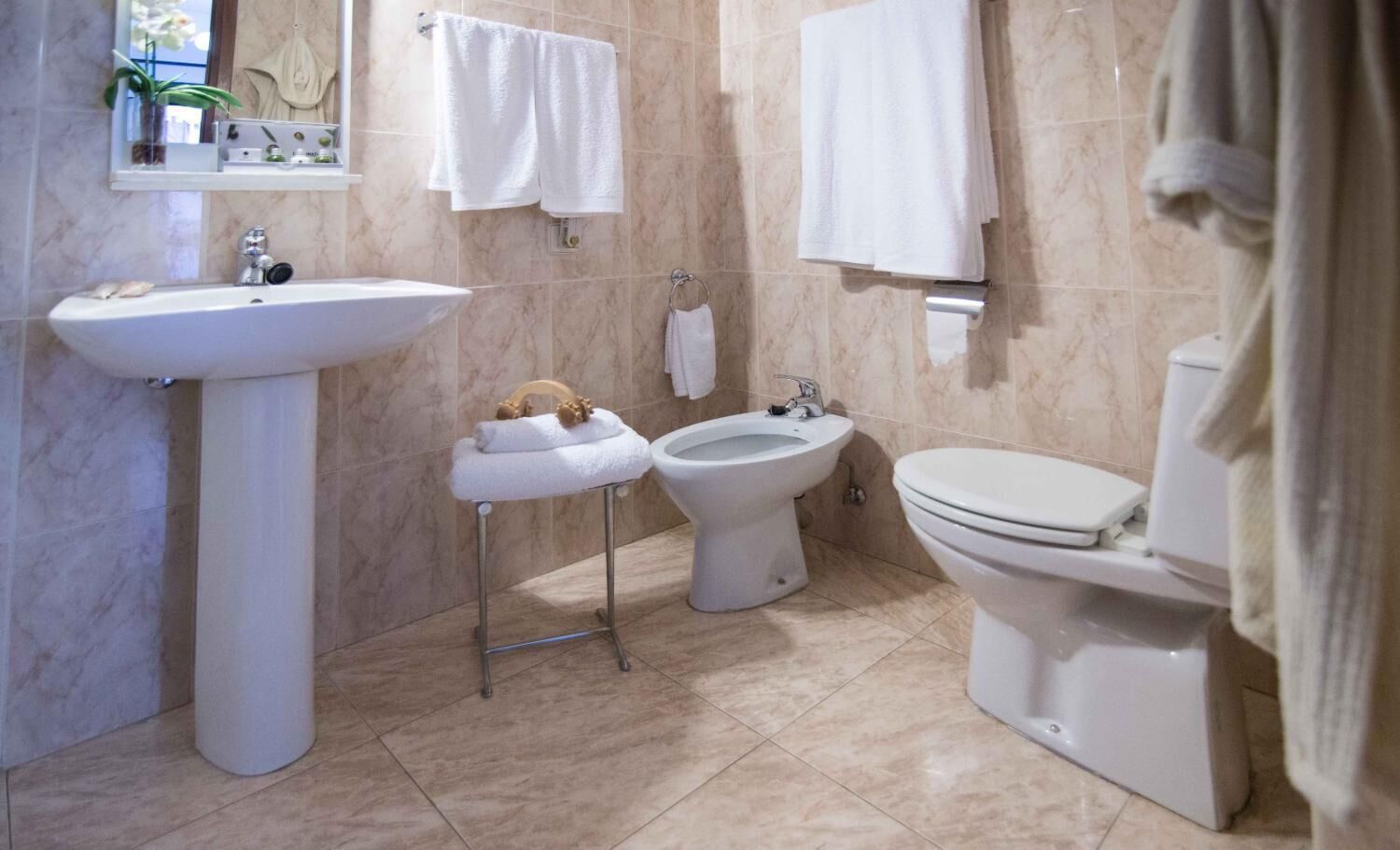 Une salle de bain équipée d’un lavabo sur colonne, d’un bidet, de toilettes et d’un porte-serviettes.