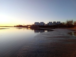 A calm body of water reflecting buildings, with a clear sky and a distant horizon. - Villa Miri (Privlaka)