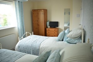 Ein Schlafzimmer mit Bett, Kommode, Fernseher und Kleiderschrank.