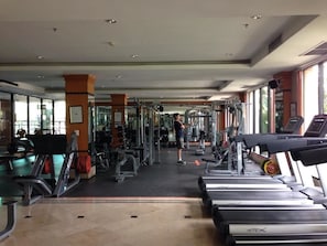 Ein Fitnessstudio mit Laufbändern, Kraftgeräten und einer trainierenden Person.