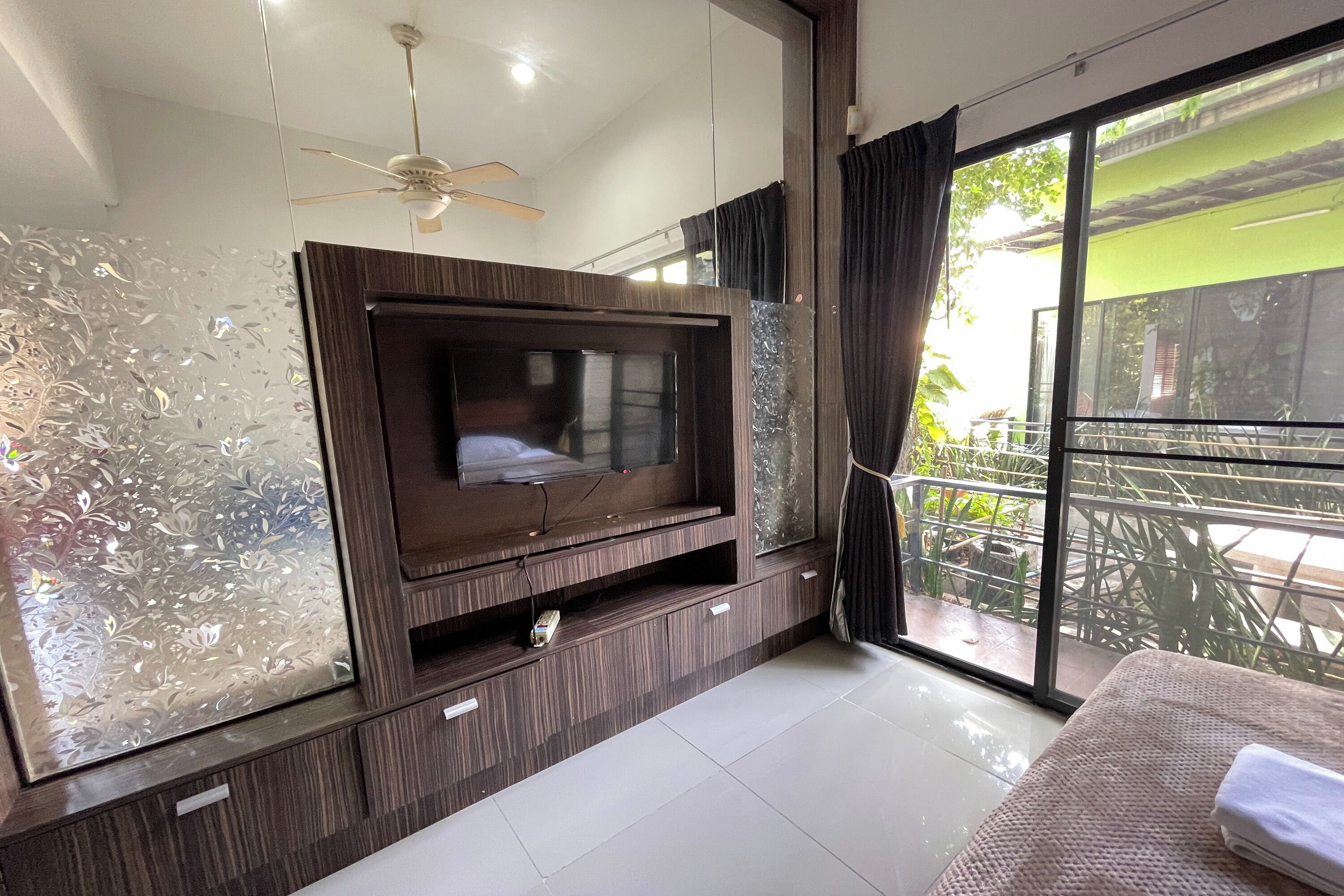 Een moderne kamer met een grote flatscreentelevisie, een plafondventilator en een balkon met uitzicht.
