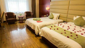 A hotel room with two beds, a wooden floor, a sitting area with chairs, and a large window with curtains. - K Raphael Hotel (Xi'an)