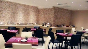A modern dining area with white and black chairs, a central bar, and a patterned wall. - K Raphael Hotel (Xi'an)