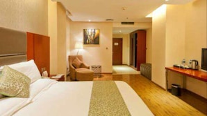 A hotel room with a large bed, a desk, a chair, and a small table. - K Raphael Hotel (Xi'an)