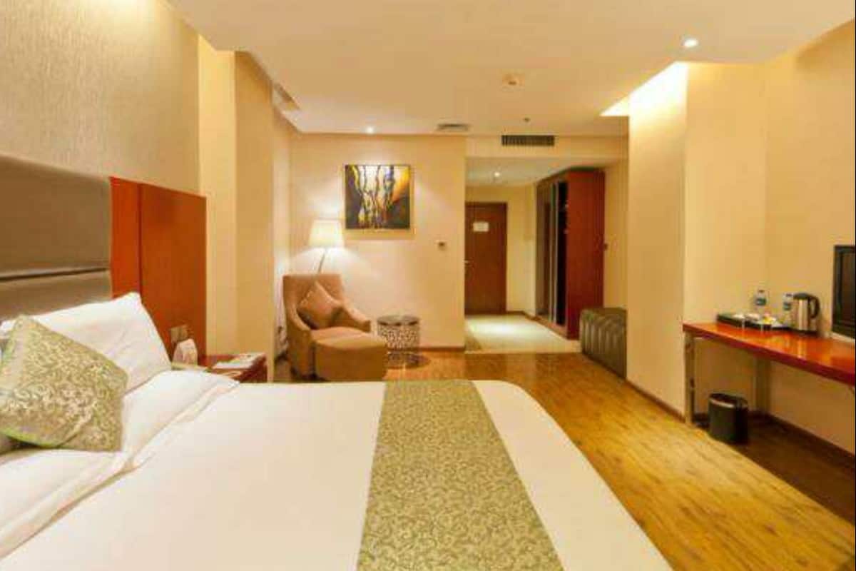 A hotel room with a large bed, a desk, a chair, and a small table.