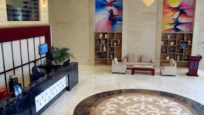 A hotel lobby with a reception desk, seating area, and decorative paintings. - K Raphael Hotel (Xi'an)