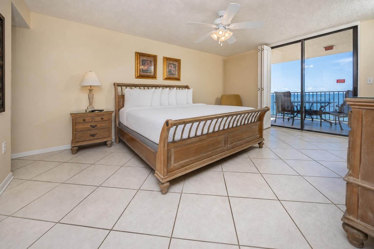A bedroom with a bed, a nightstand, a lamp, and a ceiling fan.