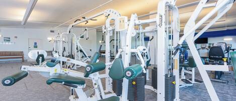 A gym with various exercise machines, a bench, and a mirrored wall.